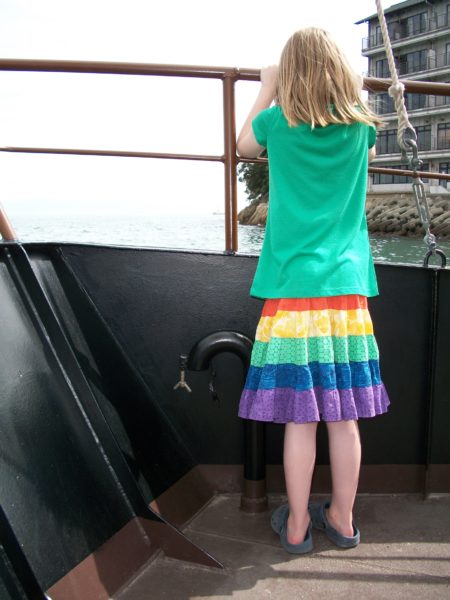 girl on a boat wearing a rainbow skirt made with strips of gathered fabric