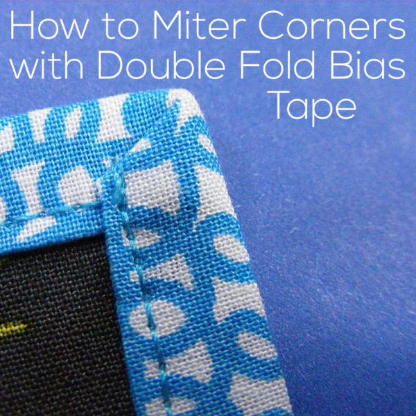 Close up photo of one mitered corner. Text reads: How to Miter Corners with Double Fold Bias Tape - video tutorial from Shiny Happy World