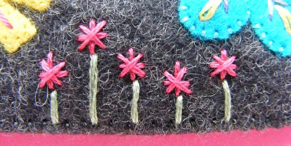 pink star flowers embroidered on dark grey felt
