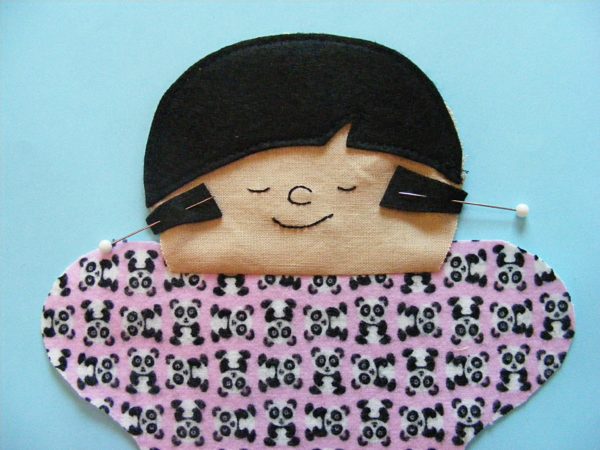 partially sewn doll with pigtails pinned in place