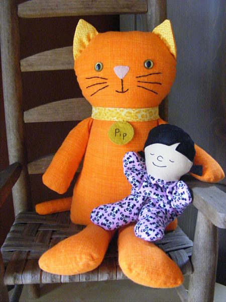 finished Itty Bitty Sleepy Baby sitting in the lap of a Pip the Cat doll - both patterns from Shiny Happy World