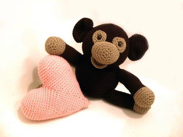 Soft crocheted monkey holding a pink heart plush toy, perfect for children's toys and handmade crochet gifts.