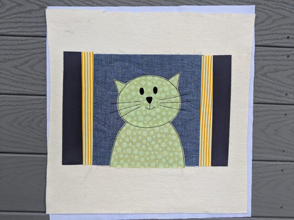 Applique cat with side pieces of frame sewn in place