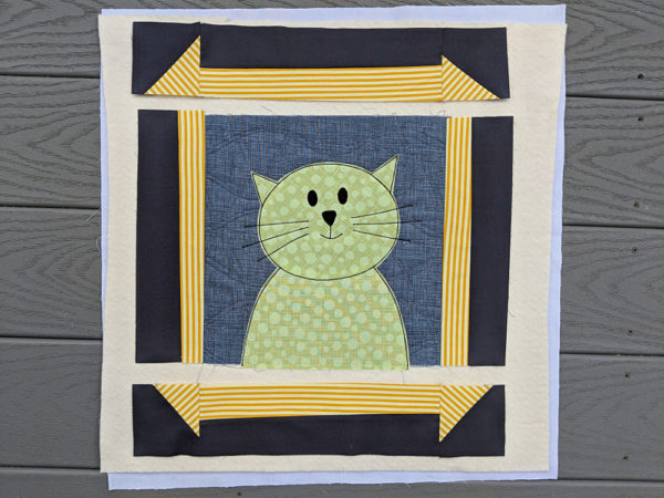 applique cat with top and bottom strips of frame sewn together