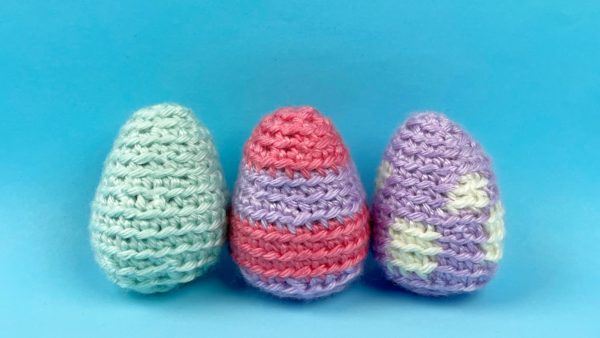 Row of three colorful crocheted Easter eggs - one solid, one striped, and one polkadot