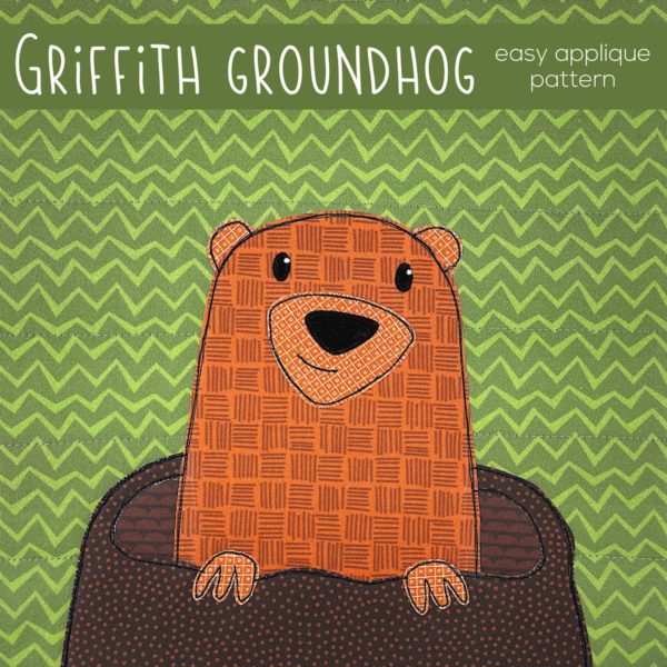 Cute groundhog popping out of his burrow - appliqued on brown fabric on a green zigzag background. Text reads: Griffith Groundhog - easy applique pattern