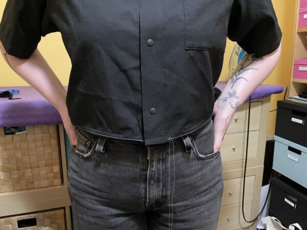 Close-up of a person wearing a black shirt white basting at the hem.