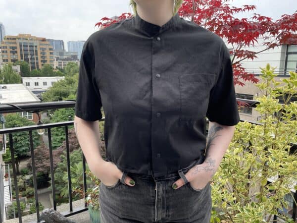 Person wearing a black shirt with a stand collar on a balcony.